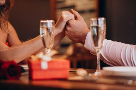 couple se tenant la main devant une flute de champagne