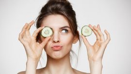 femme avec deux rondelles de concombre devant les yeux