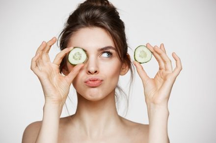 femme avec deux rondelles de concombre devant les yeux