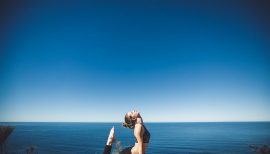femme sur un tapis de yoga face à la mer