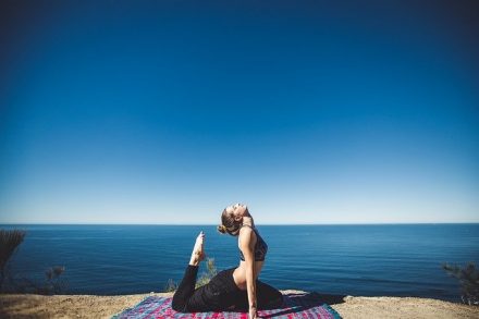 femme sur un tapis de yoga face à la mer