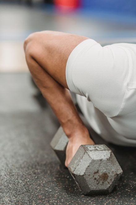 gros plan sur triceps homme faisant une pompe avec haltère