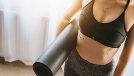 femme en brassière ventre apparent portant un tapis de gym