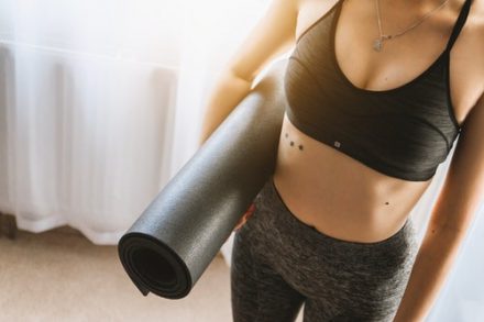 femme en brassière ventre apparent portant un tapis de gym