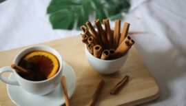 bol empli de bâtons de cannelle et tasse de thé citron sur planche de bois