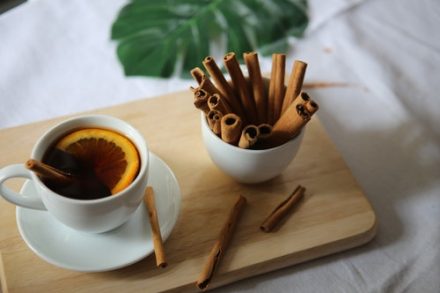 bol empli de bâtons de cannelle et tasse de thé citron sur planche de bois