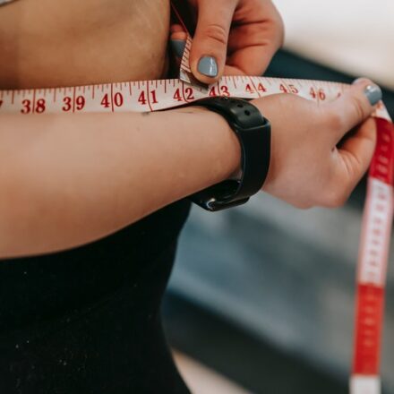 femme se mesurant le tour de taille à l'air d'un mètre