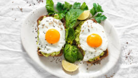 assiette composée de deux avocado toasts avec des oeufs sur le plat.