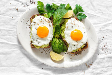 assiette composée de deux avocado toasts avec des oeufs sur le plat.