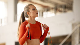femme coiffée d'une queue-de-cheval et vêtue d'orange au gym
