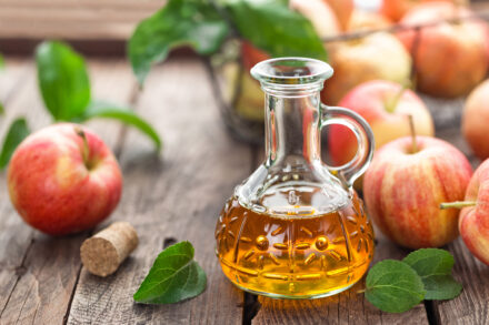 Vinaigre de cidre et pommes posés sur une table en bois