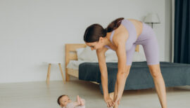 jeune maman sportive en train de s'entraîner sur tapis de gym avec son bébé