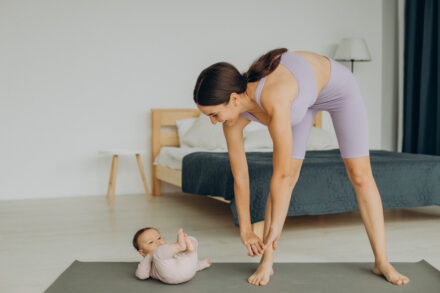 jeune maman sportive en train de s'entraîner sur tapis de gym avec son bébé