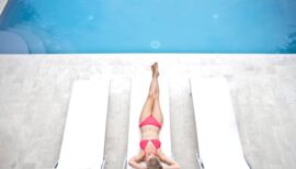 femme en maillot de bain allongée sur un transat au bord d'une piscine
