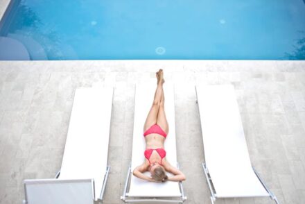 femme en maillot de bain allongée sur un transat au bord d'une piscine