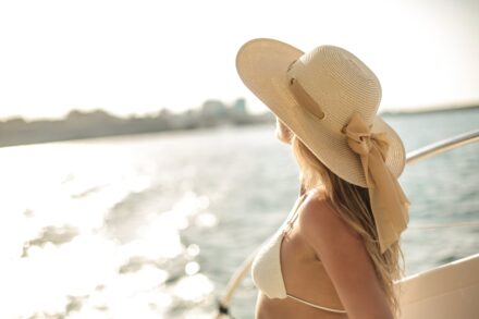 femme sur un bateau coiffée d'un chapeau, en maillot de bain.