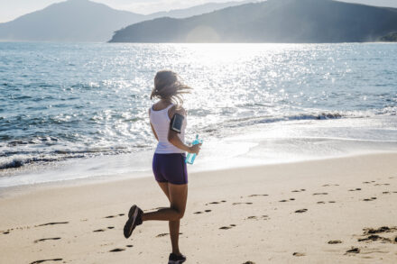 sportive en train de courir sous le soleil sur la plage