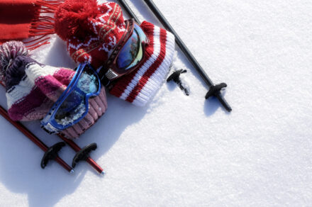 bonnets de ski et lunettes posés sur la neige, avec des bâtons