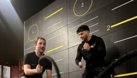 Séance de personal training à Genève dans une salle de sport haut de gamme, avec coach sportif et cliente en pleine exécution d’un exercice de renforcement musculaire.