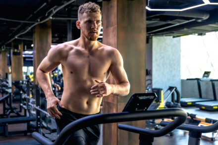 homme en salle de sport, courant sur un tapis de course pour gommer ses poignées d'amour