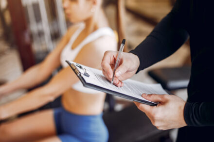 femme faisant du sport avec un coach qui prend des notes