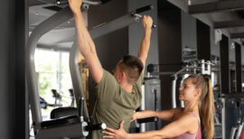 homme passant sa première traction, assisté par une coach sportive