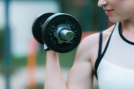 femme faisant preuve de force musculaire avec un haltère