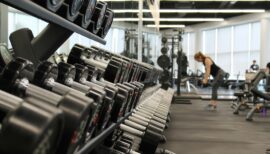 plan serré sur des haltères et femme qui s'entraîne en salle de sport