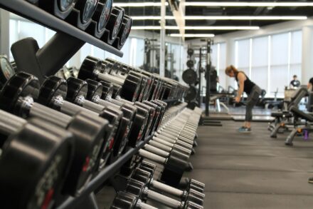 plan serré sur des haltères et femme qui s'entraîne en salle de sport
