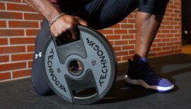 homme tenant un disque lesté pour faire sa musculation