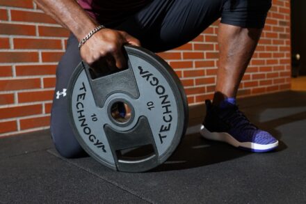 homme tenant un disque lesté pour faire sa musculation