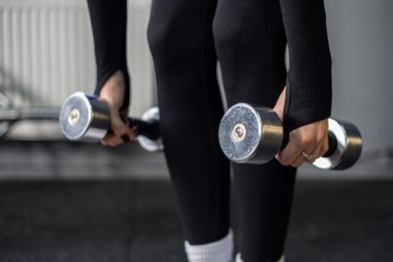 femme tenant des charges de musculation (haltères)